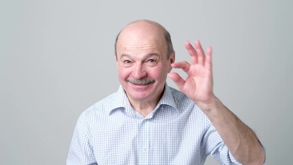 Senior man with mustache showing something small with figers.