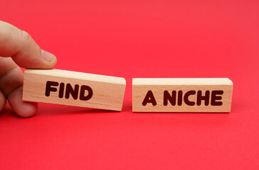 On a red background, wooden blocks, one of them in hand. The blocks are written - Find a niche - obrazy, fototapety, plakaty