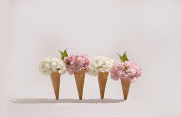 Spring flower in ice cream cone on light background. Minimal spring concept idea.