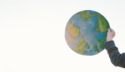 Protection and love of earth. Little boy holding planet in hands against green spring background. Earth day concept. Environmental Conservation