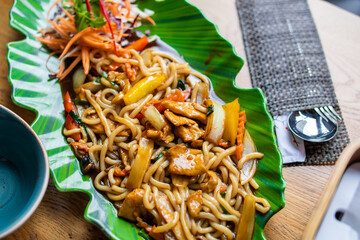 Soba, udon, asian wheat noodles with chicken and vegetables in green plate