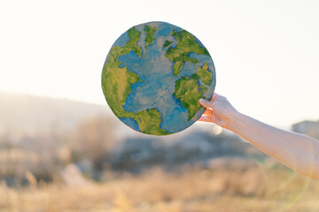 Protection and love of earth. Woman holding planet in hands against green spring background. Earth day concept. Environmental Conservation
