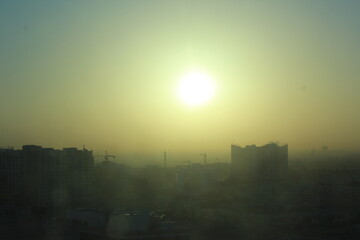 Amanecer, sol cubierto de smog, niebla y humo, aire urbano contaminado