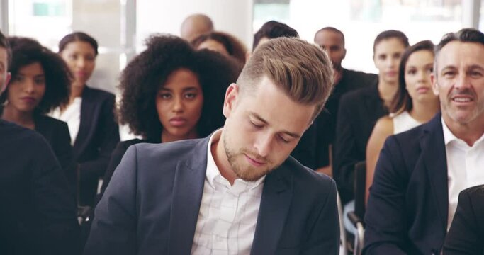 You definitely have my attention. 4k video footage of businesspeople sitting in a convention center during a conference.