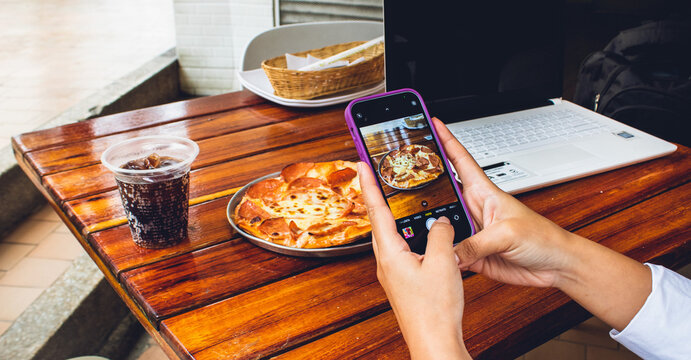mano de persona influencer con celular tomando foto para historias de plato con comida en restaurante
