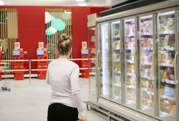 Woman choosing frozen food from a supermarket freezer.