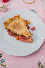 single slice of rhubarb pie on white plate, pink tablecloth with blue roses