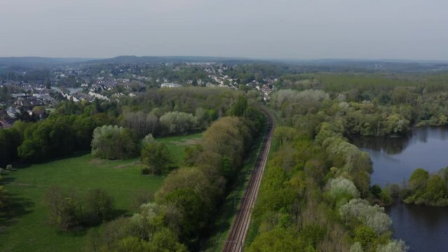 Aerial view of a train track in the countryside. Railway from a bird's eye view passing through the green forest. Filmed in 4k, drone video. Railway and small country town. 