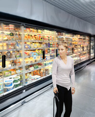 Woman choosing frozen food from a supermarket freezer.