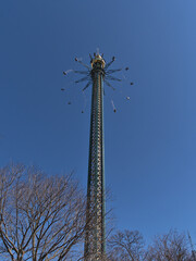 View of rotating tall drop tower in amusement park Wurstelprater in Vienna, Austria with bare trees...
