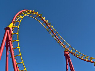 Close-up view of the red and yellow colored rails of a roller coaster in popular amusement park...