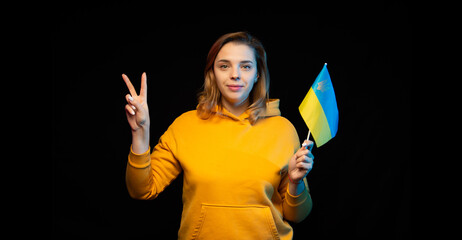 Ukraine national flag. Beautiful ukrainian girl with government flag on a stick in her hands on black background. Symbol of Ukrainian statehood