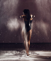 Dancer woman in bodysuit with white dust around