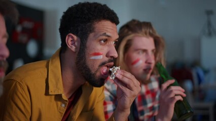 Nervous football fans friends staring at TV and watching football match at home