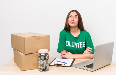 hispanic pretty woman shrugging, feeling confused and uncertain. donations volunteer