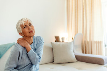 Mature woman with shoulder pain. Elderly woman is enduring awful ache. Shoulder pain in an elderly person. Beautiful lady with shoulder pain. Photo of senior woman holding her neck in pain.