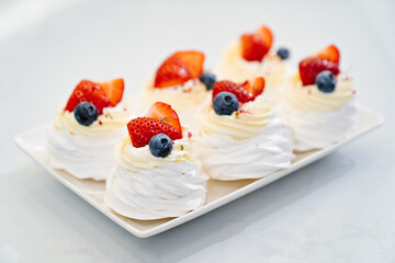 strawberries, blueberries and cream decorates to Anna Pavlova cakes.