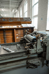Setting type on a letterpress, with wooden type cases in the background.