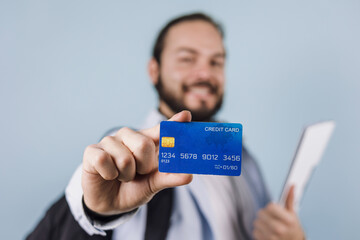 young latin man holding a credit card for shopping on blue background in Mexico Latin America	