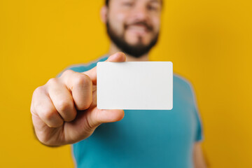 young latin man holding a blank card for shopping on yellow background in Mexico Latin America	