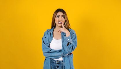 portrait of brunette young hispanic woman frustrated, worried or bored with copy space on yellow background in Mexico Latin America - obrazy, fototapety, plakaty