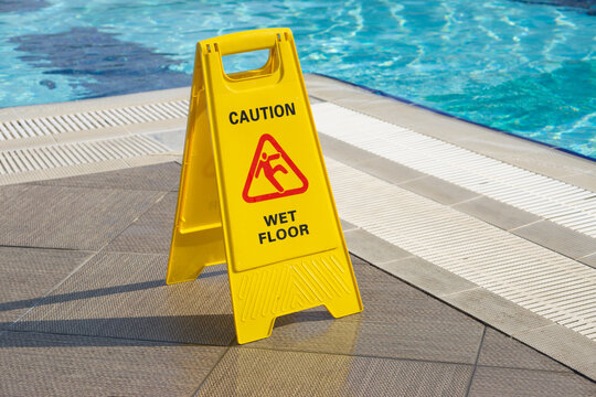 caution wet floor warning sign near swimming pool in hotel