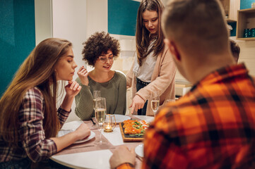 Group of friends enjoying dinner while sitting at the kitchen table together