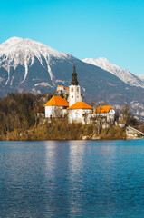 Famous alpine lake Bled (Blejsko jezero) in Slovenia, stunning autumn landscape. Panoramic view of lake, island with church, mountains and blue sky with clouds, outdoor travel background