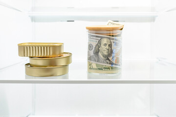 Money, cash banknotes, US dollars in a glass jar and canned food in the refrigerator. Cash saving concept, shadow economy, tax evasion, bad economic decision