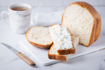 Home made bread on a wooden cutting board with curd cheese