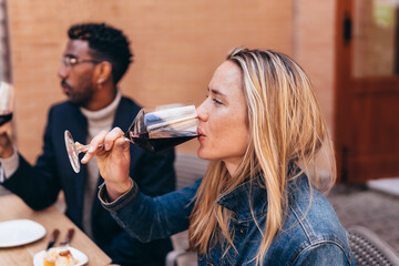young Caucasian woman drinking red wine from a glass