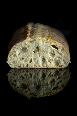 freshly baked artisan ciabatta bread on black mirror kitchen table. close up photo on the table