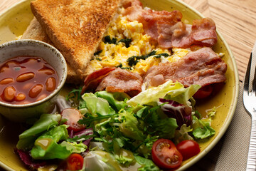 Poached eggs with vegetable, ham, tomatoes, red beans and sourdough toast isolated on wood background. Homemade food. Tasty breakfast.