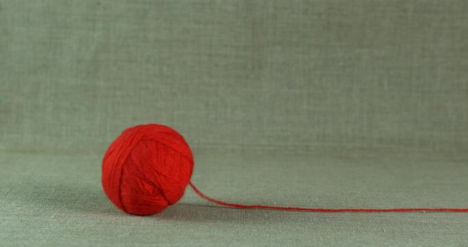 Rolling wool ball. A view of red woolen ball rolling on the floor in the room.