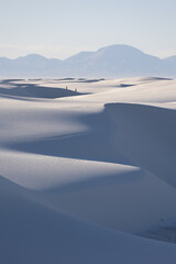 Fototapeta na wymiar Two hikers in the distance traverse the gypsum sand dunes in White Sands National Park