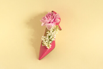 Minimal concept with blooming white lilac and pink peony in a shoe. Creative idea on beige background. 