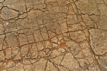 Pattern of cracks in old concrete pavement in colours of grey and brown. 