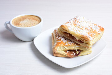 Puff pastry cake with arequipe and cheese, grated coconut, accompanied by Colombian coffee on a wooden background