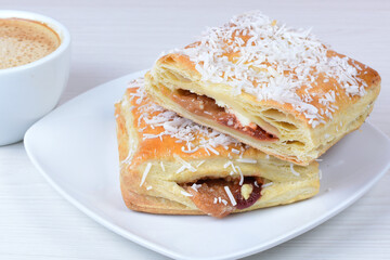 Puff pastry cake with arequipe and cheese, grated coconut, accompanied by Colombian coffee on a wooden background