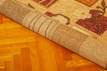 Rolled carpet on the floor in the living room close-up. The concept of cleaning the room. The carpet is rolled up to free the floor for cleaning.