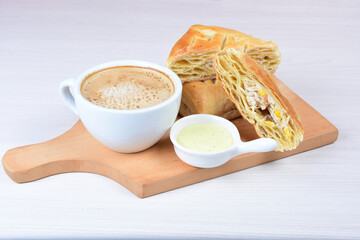 Chicken and cheese puff pastry, accompanied by corn sauce and a cup of Colombian coffee on a wooden background