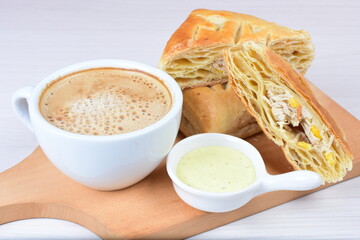 Chicken and cheese puff pastry, accompanied by corn sauce and a cup of Colombian coffee on a wooden background