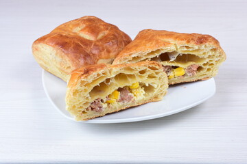 Ham and corn puff pastry, accompanied by sauce on a wooden background