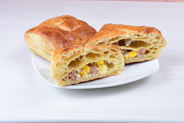 Ham and corn puff pastry, accompanied by sauce on a wooden background