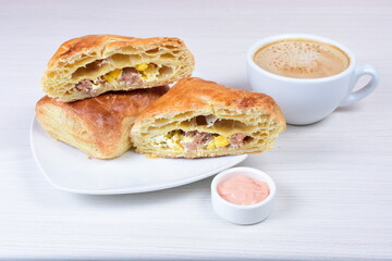 Ham and corn puff pastry, accompanied by sauce on a wooden background