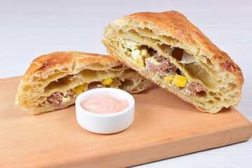 Ham and corn puff pastry, accompanied by sauce on a wooden background