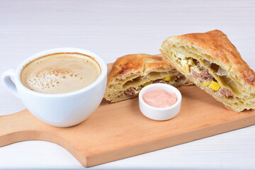 Ham and corn puff pastry, accompanied by sauce on a wooden background