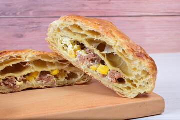 Ham and corn puff pastry, accompanied by sauce on a wooden background
