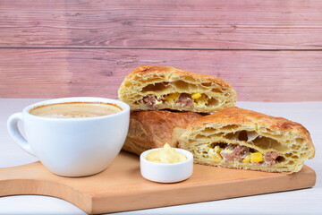 Ham and corn puff pastry, accompanied by sauce on a wooden background