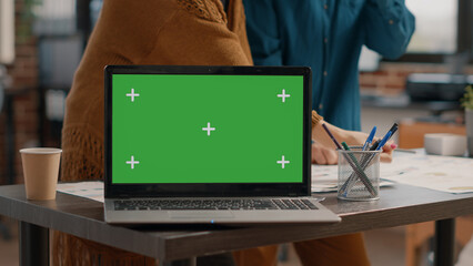 Close up of laptop with horizontal green screen on desk at startup office. Computer with isolated...